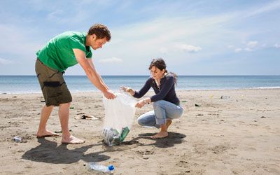Two people cleaning up a beach