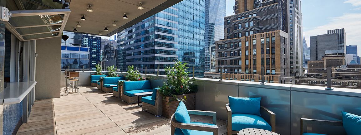 5 Oclock Somewhere Bar Times Square Bar exterior sitting area with turquoise colored chairs and balcony overlooking Times Square.jpg