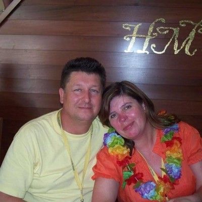 Man and woman smiling together at an event wearing tropical leis