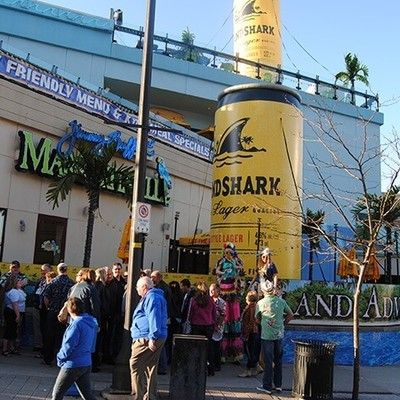 Street view of guests gathering outside near a giant LandShark beer can structure