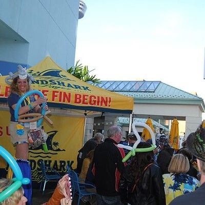 Outdoor event area with LandShark tent and guests with balloon hats
