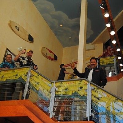 Guests holding up drinks on a staircase and balcony level