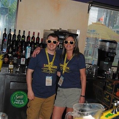 Man and woman wearing matching LandShark shirts and sunglasses behind the bar