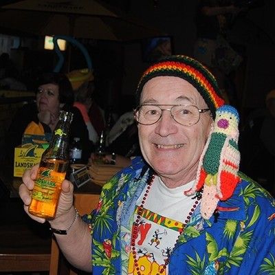 Smiling man in a colorful tropical shirt holding a LandShark beer