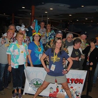 Group of party guests posing together behind an event banner