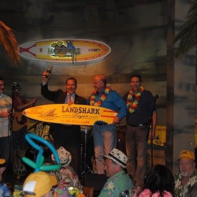 Men on stage holding a LandShark surfboard sign during a live event