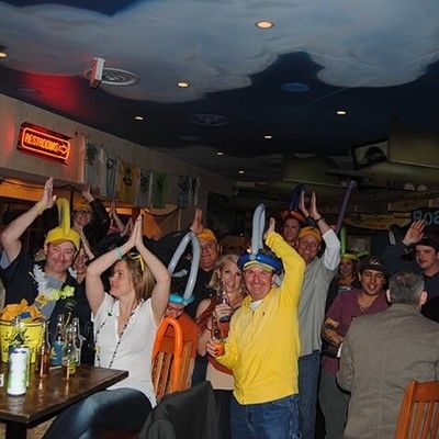 Crowd of people cheering and wearing balloon hats at a party
