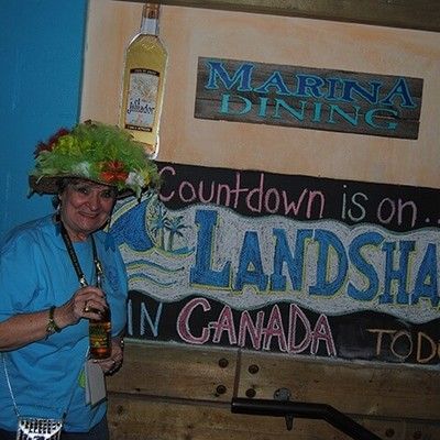 Woman in a tropical hat standing near a LandShark Canada event sign