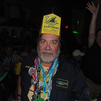 Man wearing a LandShark paper hat and event lanyards smiling at the camera