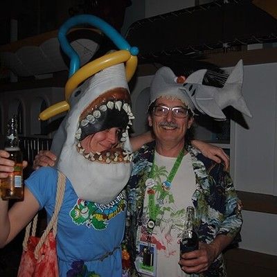 Two party guests wearing shark plush hats posing together
