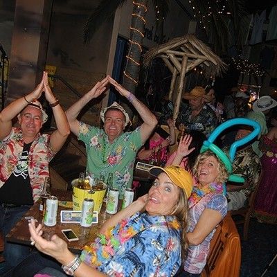 Party guests making shark fin hand signs and wearing balloon hats at their table