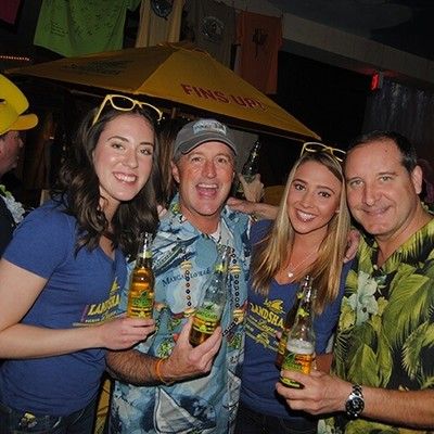 Group of people posing with LandShark beer bottles at an indoor event