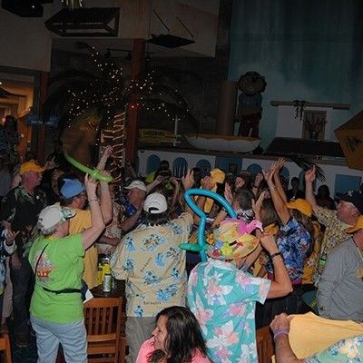 Crowd of people dancing and celebrating with balloon hats at a party