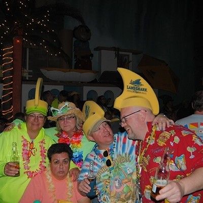 Group of friends in bright tropical outfits and foam shark hats smiling together