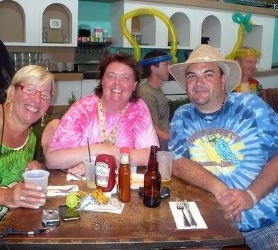 Three smiling friends sitting at a restaurant table with drinks and condiments