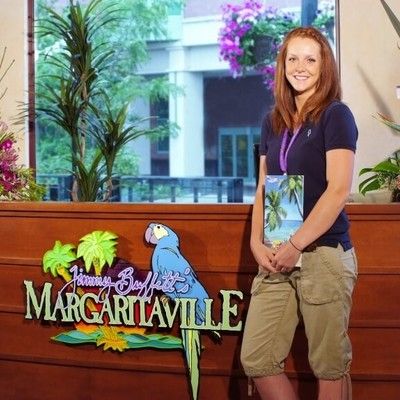 Friendly Margaritaville hostess holding menus standing by the entrance podium