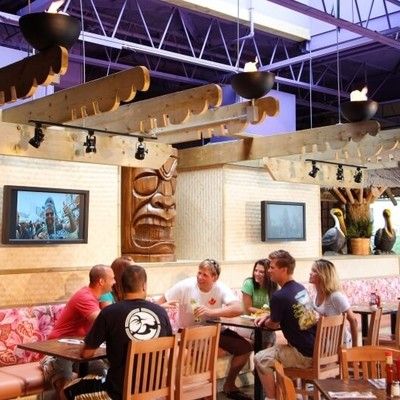 Group of guests dining in a tropical tiki-themed booth area
