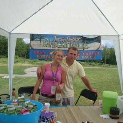 Man and woman posing together behind a Margaritaville event refreshment table