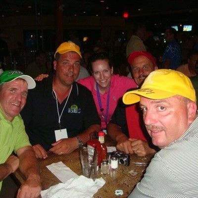 Group of guests in baseball caps and golf shirts sitting together at a table