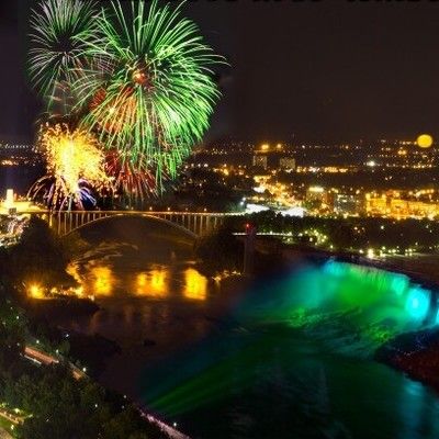 Nighttime aerial view of fireworks exploding over illuminated Niagara Falls