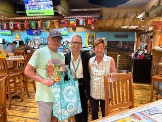 Three event organizers posing together indoors with Margaritaville gift bags