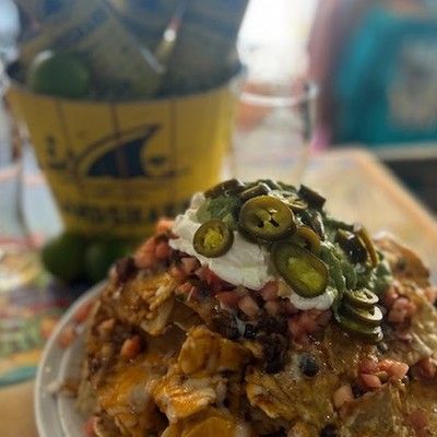 Photo go loaded nachos topped with melted cheese, sliced jalapeños, sour cream, and salsa