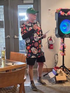 Event speaker in a floral Hawaiian shirt presenting at the indoor gathering