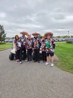 A group of tournament participants in matching sombreros and colorful outfits posing on the golf path