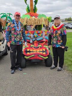 Participants posing next to a brightly decorated tropical-themed golf cart