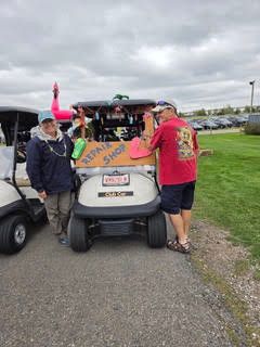 Golfers standing next to a decorated golf cart at the golf course