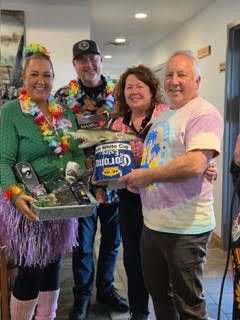 Four participants smiling and presenting raffle prizes inside the venue