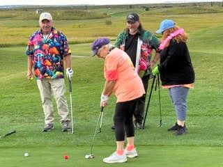 Golfer lining up a putt on the green while fellow participants look on