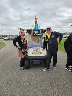 Golfers posing on the course next to a decorated golf cart with a giant inflated bottle