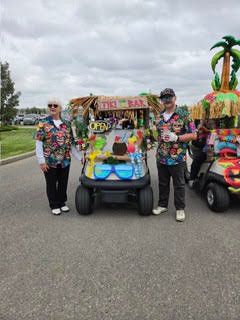 Participants walking alongside colorful tropical-themed golf carts on the paved path