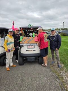 Group of golfers in bright Hawaiian shirts posing next to their decorated golf cart