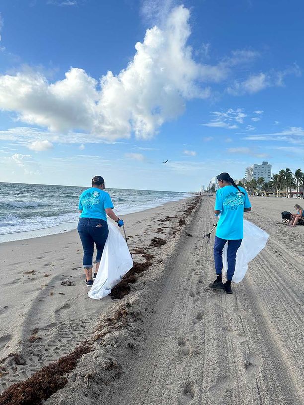 Two women with bags helping to clean up any garbage on the beach
