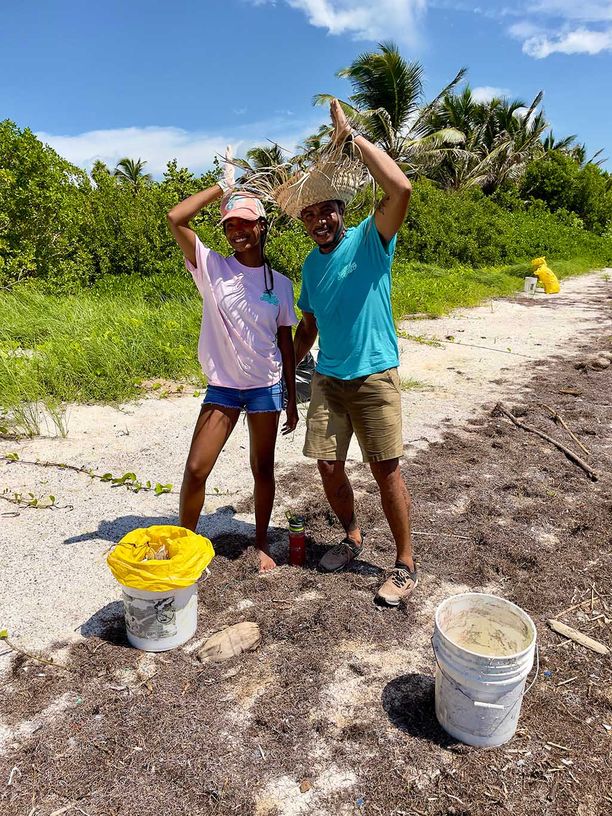 Man and a woman making the fins up sign with their hand while helping to clean the beach