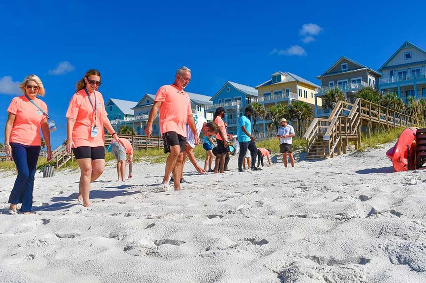 People walking on the beach with multiple colorful beach homes behind them