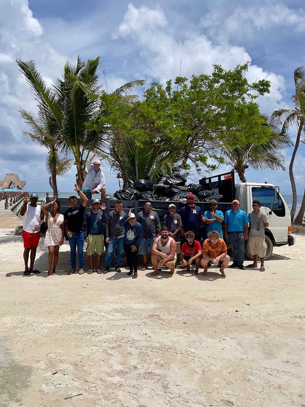 Group of people in front of a truck that is hauling away garbage collected from the beach