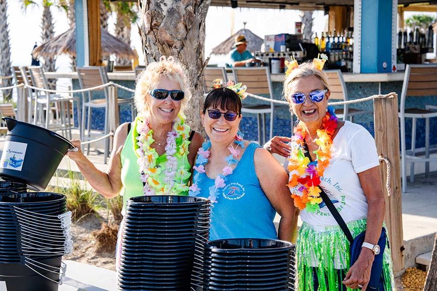 Three women in sunglasses smiling and wearing lei necklaces