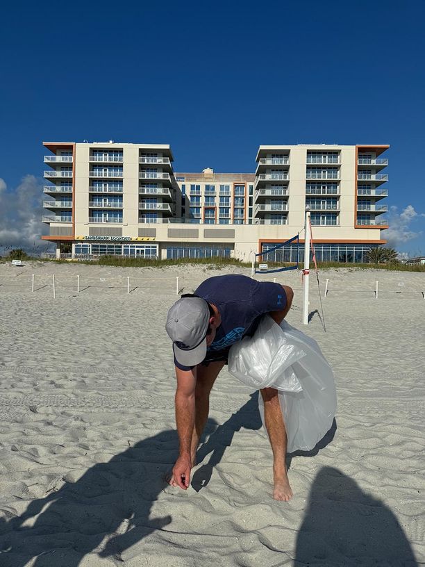 Man bending over to pick up something in the sand