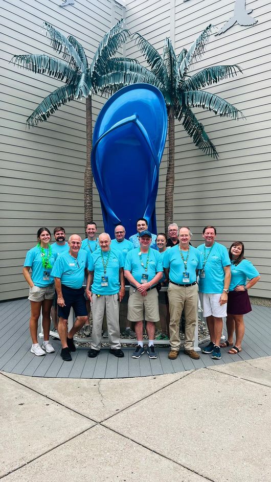 Group of people standing in front of a large blue sandal