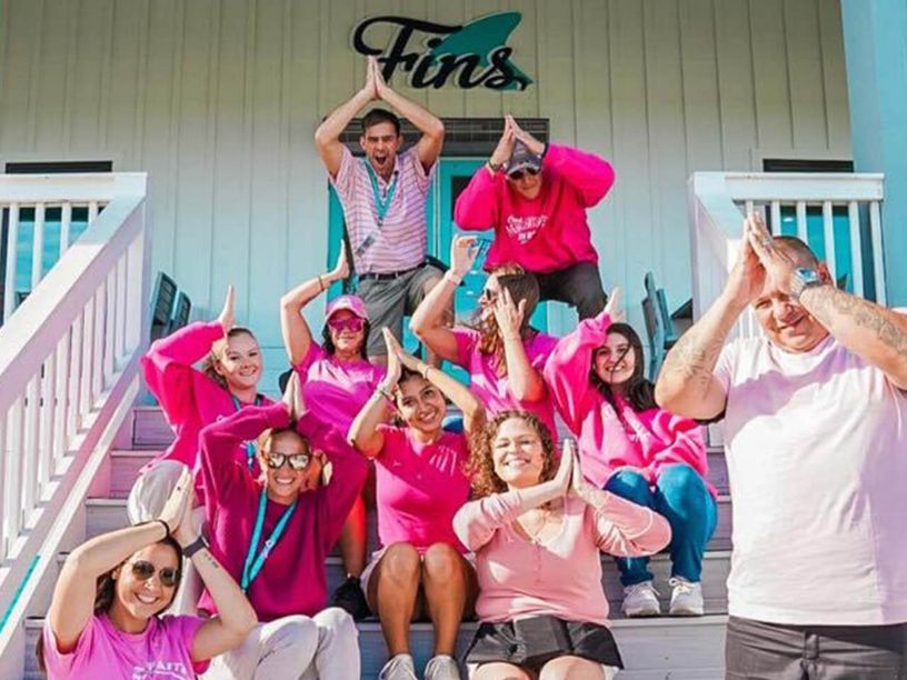 Group of people smiling while doing the fins up sign above their heads