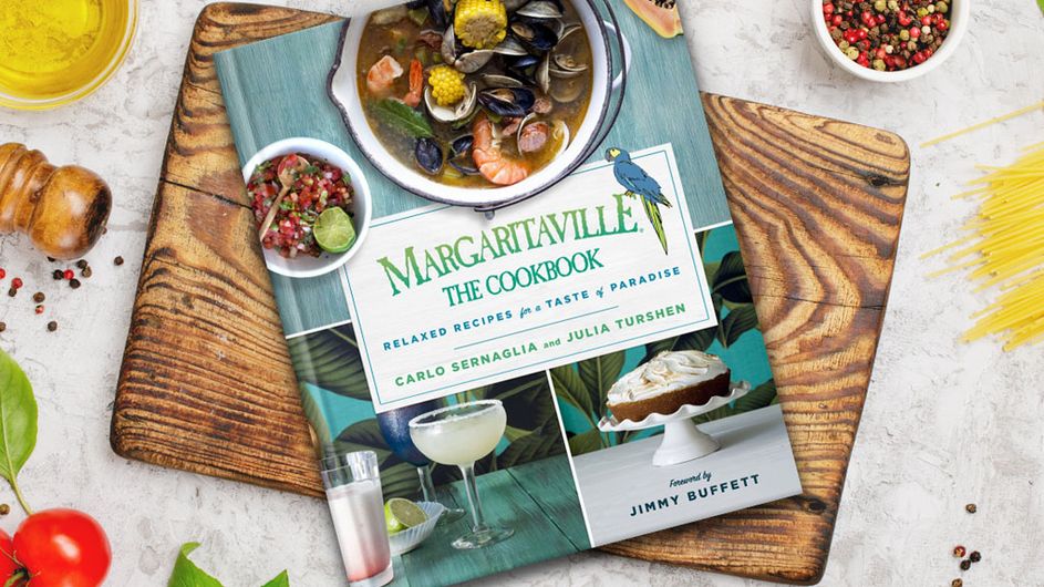 Margaritaville Cookbook lying on a cutting board on a table of food