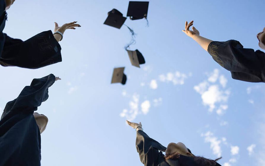 Looking up form the ground of graduates throwing their caps high in the air