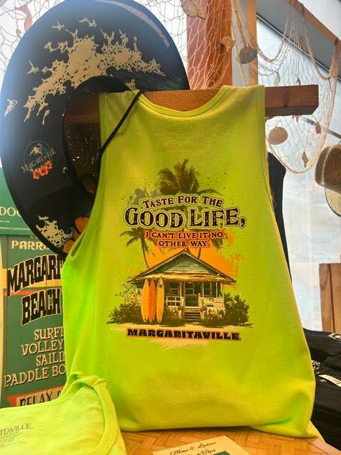 Neon green Margaritaville tank top displayed on a wooden stand reading 'Taste for the Good Life'