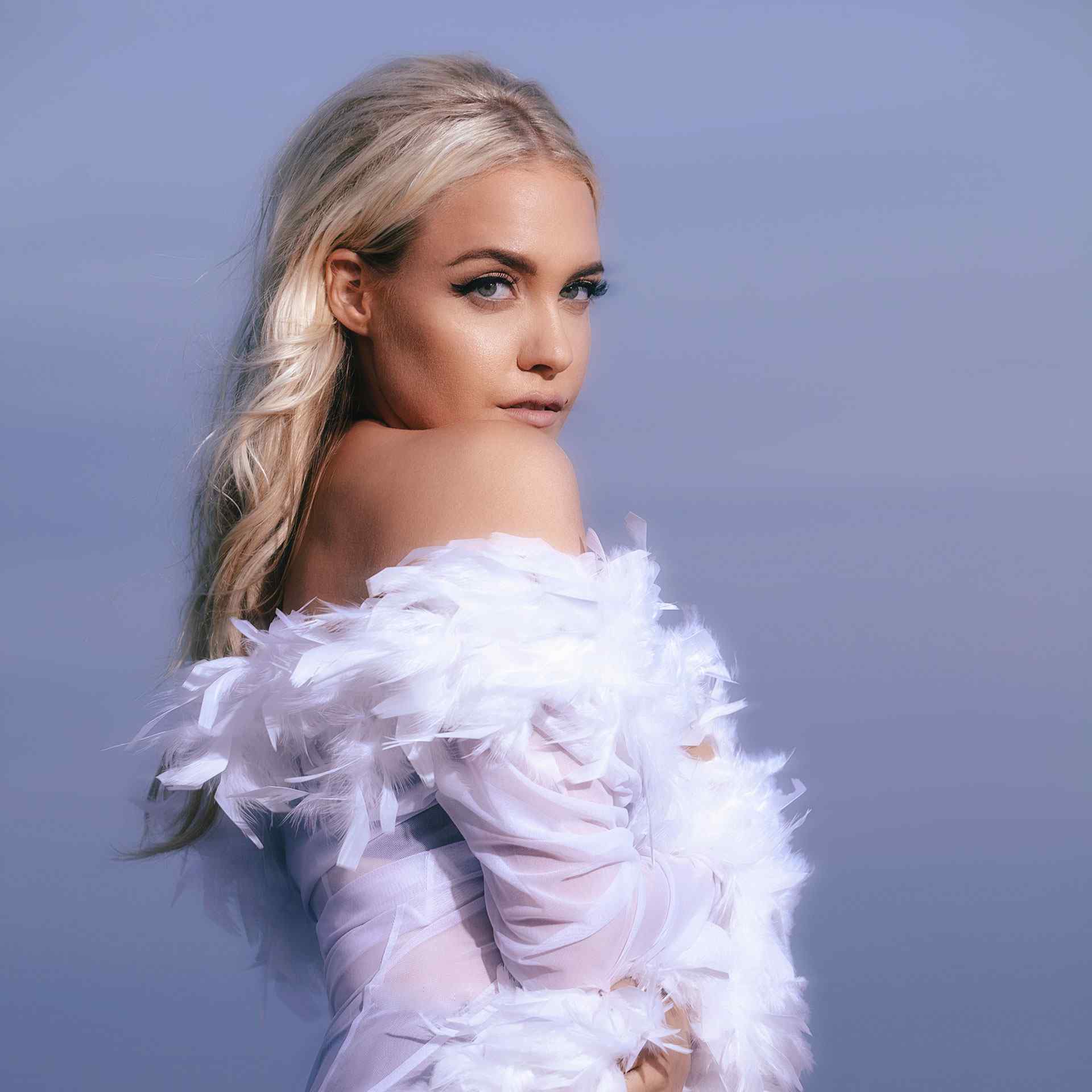 Eden wearing pink ruffled dress standing in front of a light purple pastel background