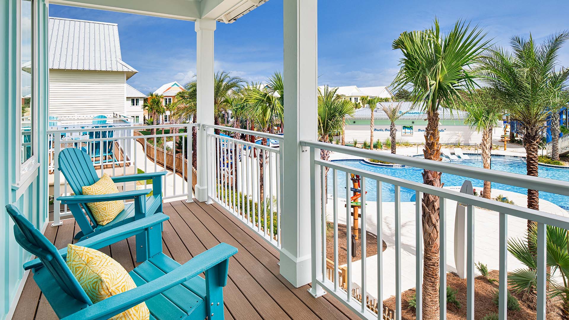 hero_4.jpg A balcony view overlooking a pool with blue chairs.