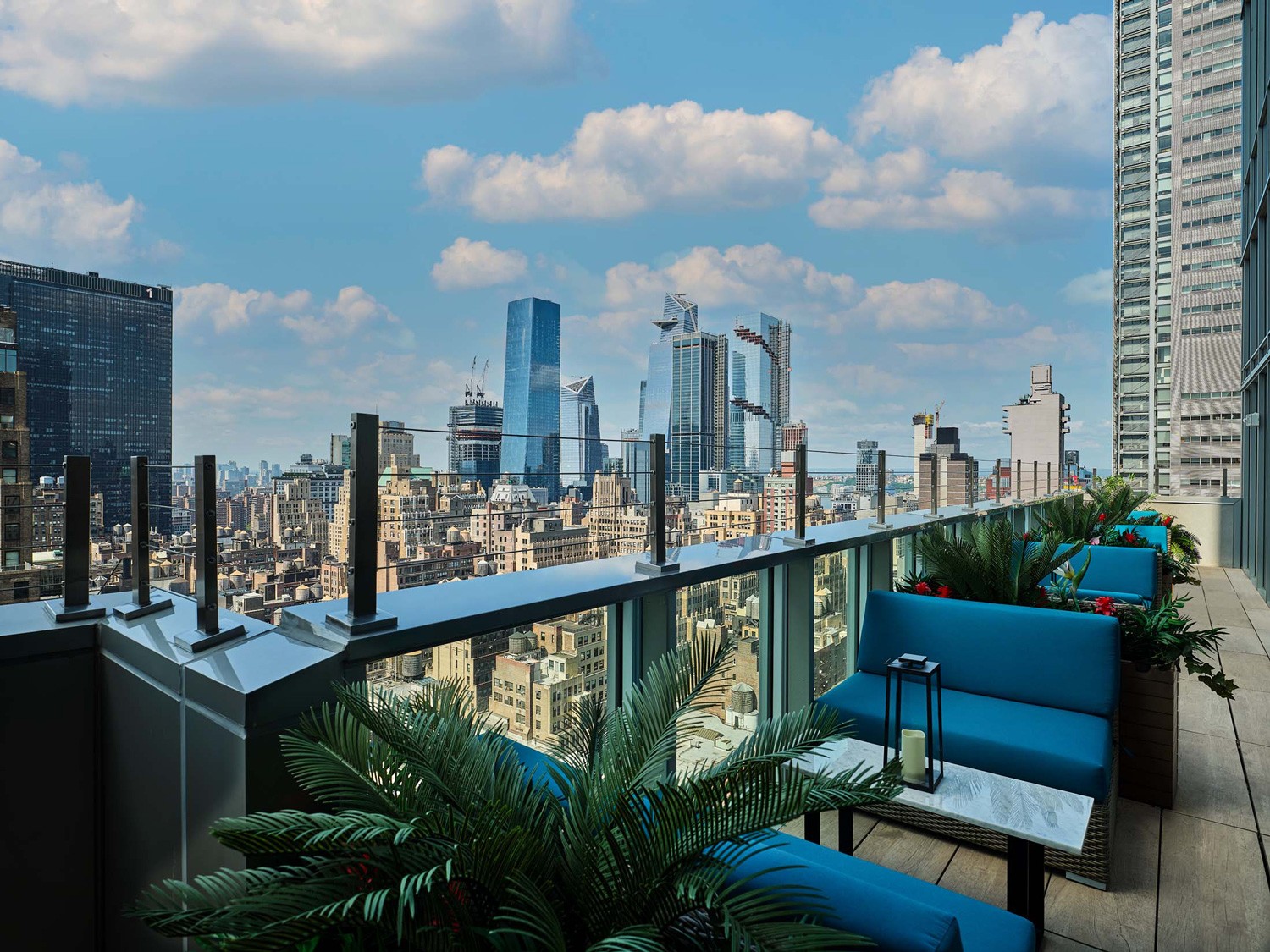5 Oclock Somewhere Bar Times Square Rooftop patio with turquoise chairs and a view of lower Manhattan skyline during the day