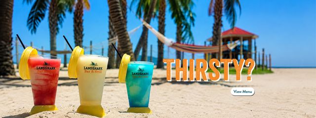 Blender cups with frozen beverages on the beach. Thirsty? Click to view our full beverage and dining menu online.